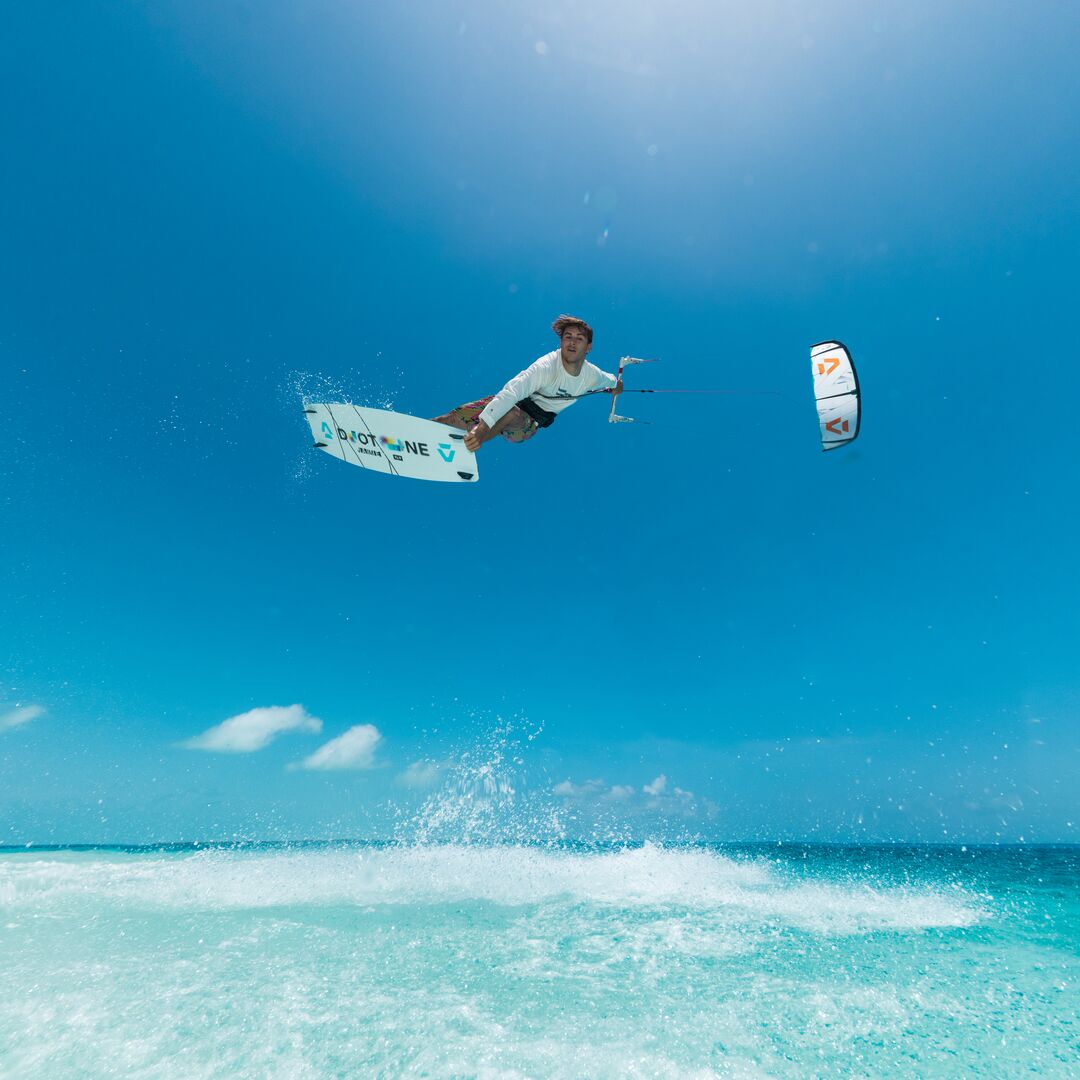 Kitesurfeur exécutant une figure aérienne avec une planche Duotone Jaime SLS dans une eau turquoise sous un ciel bleu éclatant