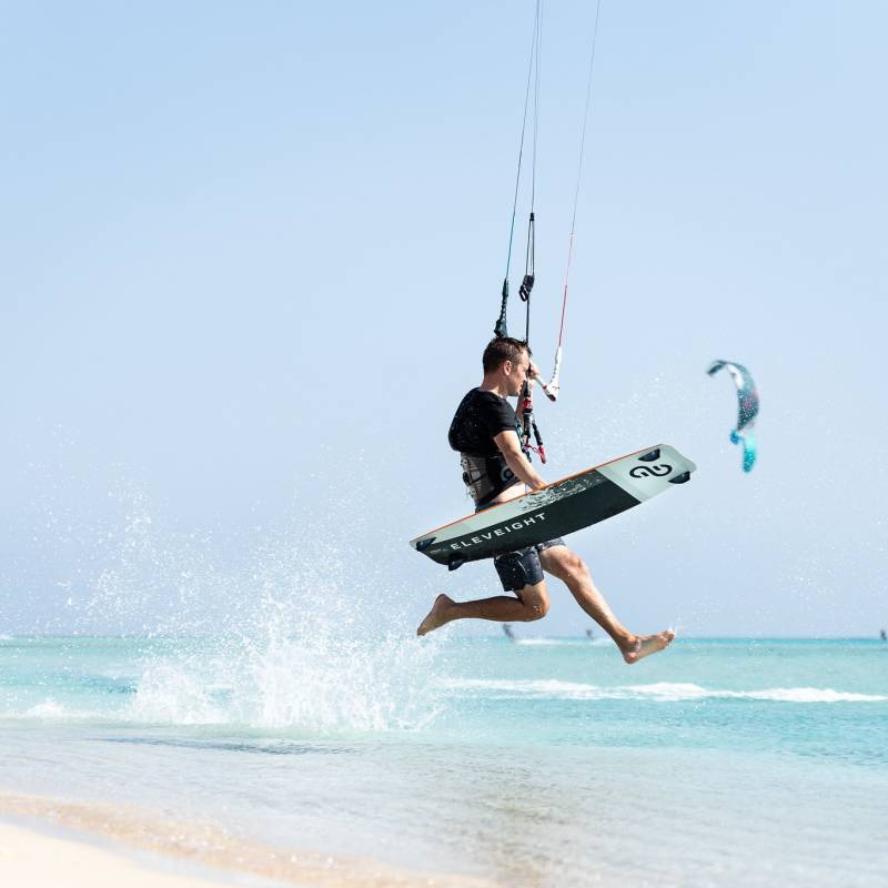 Rider en kitesurf effectuant un saut avec la planche Eleveight Process C+ V6 sur une plage tropicale
