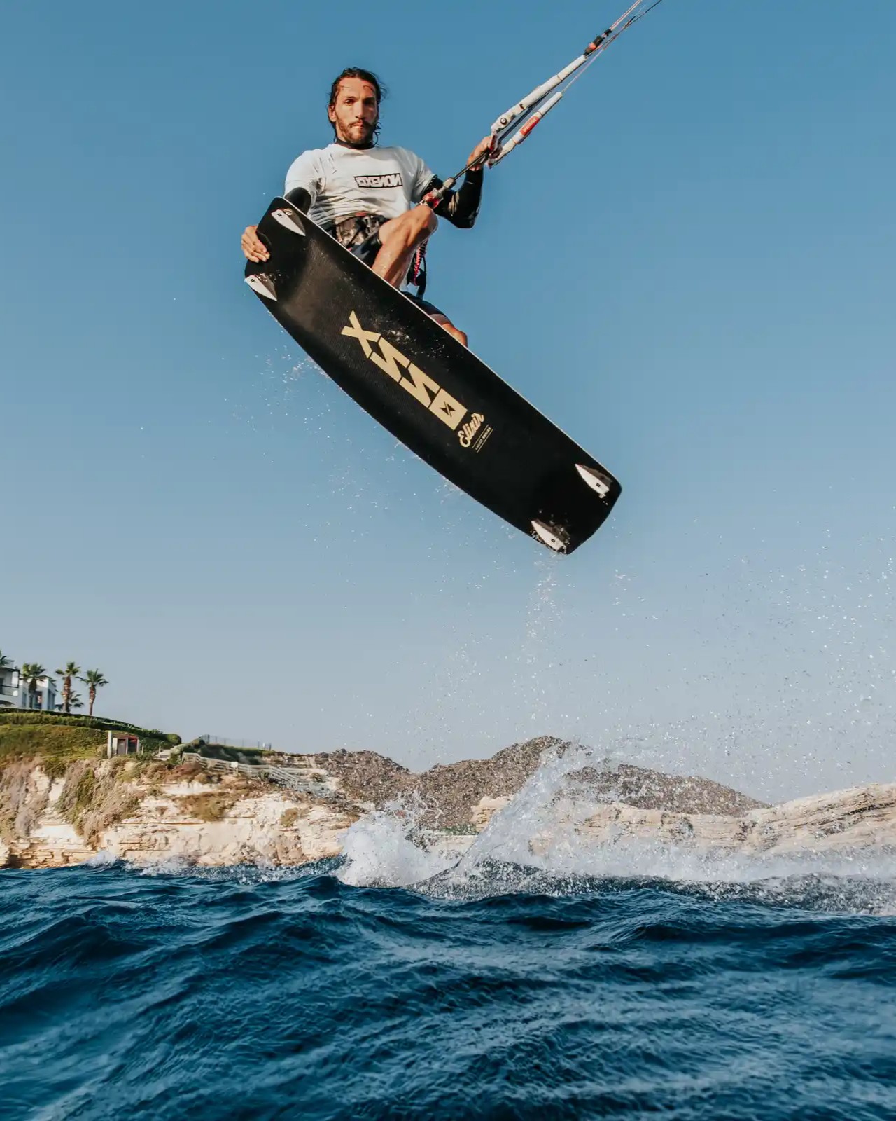 Saut en kitesurf avec la planche Xenon BSSX, puissance et hauteur au-dessus des vagues dans un spot rocheux.